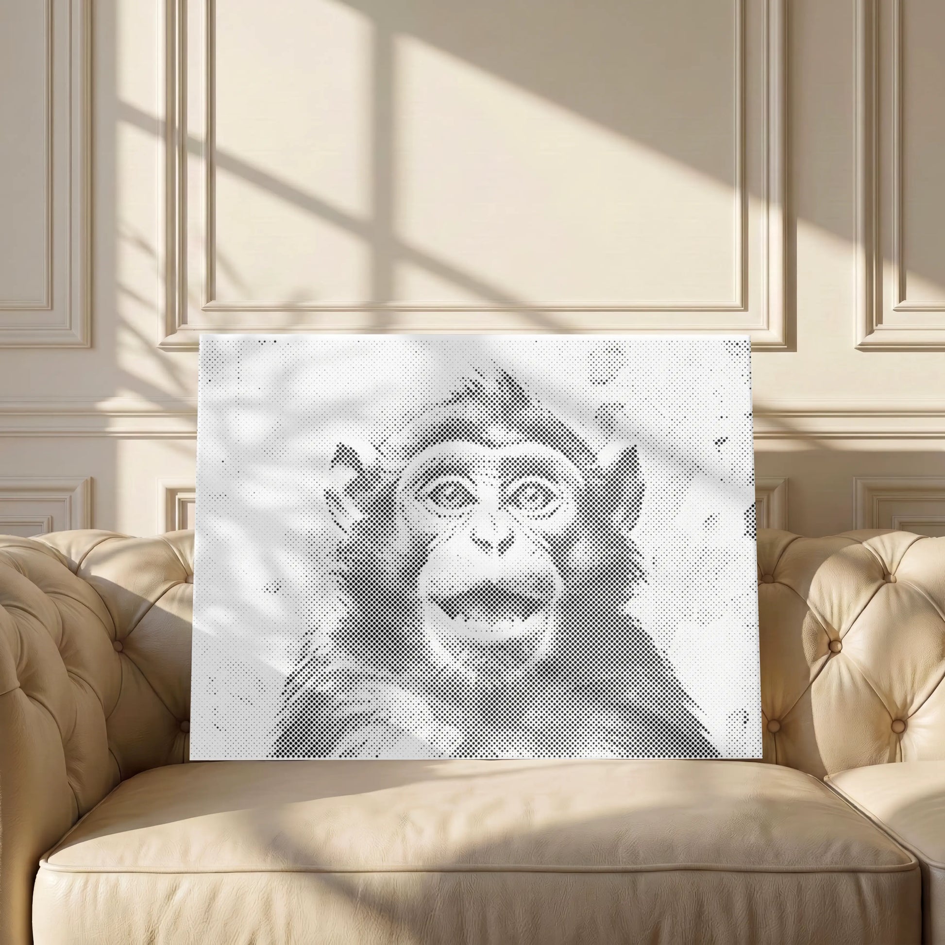 A rectangular wall art print featuring a black-and-white sketch of a monkey face, displayed on a beige tufted sofa in a sunlit room with decorative paneling. Happy Monkey | Dot Painting Kit