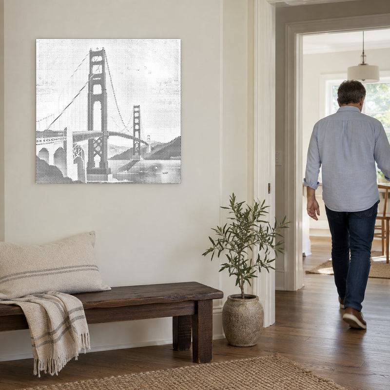Dot-painting canvas “Golden Gate Bridge”, on a light wall with a person walking through the doorway nearby.